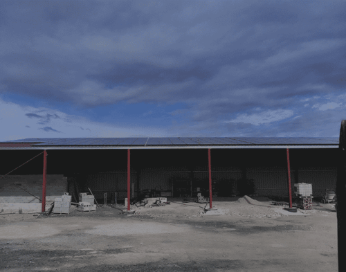 Grande structure agricole avec toit photovoltaïque sous un ciel nuageux
