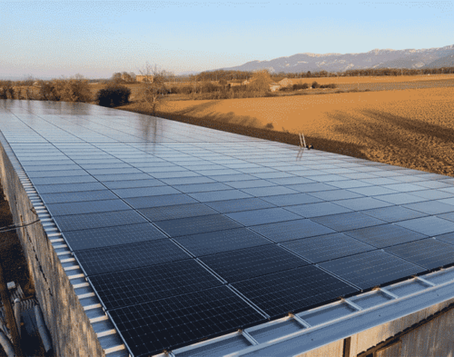 Toiture photovoltaïque sur un bâtiment agricole avec vue sur la campagne et les montagnes au loin